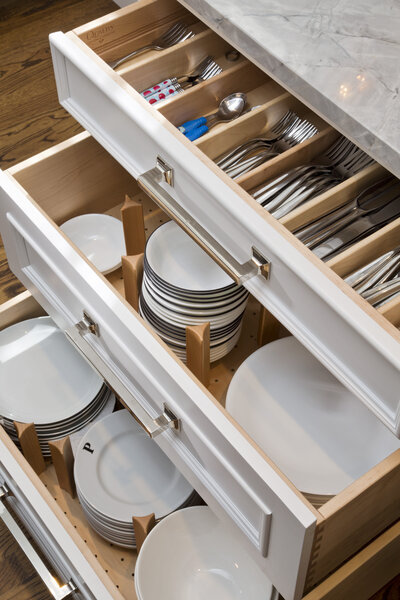 white open draws with utensils and white plateware stored