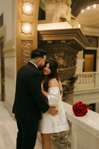 Modern city elopement with bride in short white dress and red bouquet, romantic courthouse moment captured by Tarah Shea Photography