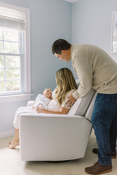  Richmond Newborn Photographer | Photo of a dad  looking over his wife's shoulder as she sits and holds their newborn baby girl by Jacqueline Aimee Portraits