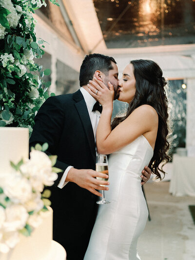 Bride and groom cutting their white tiered cake decorated with orange flowers