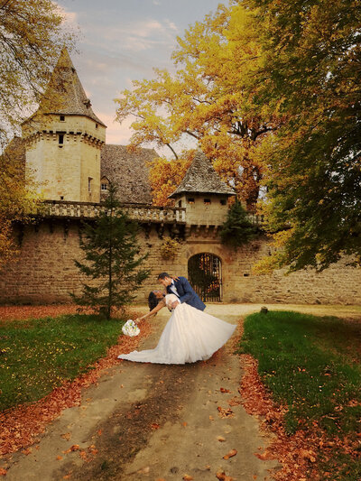 Stunning photograph capturing a bride and groom in a romantic dip, set against the grandeur of a UK castle, epitomizing the fairy-tale allure of destination weddings.