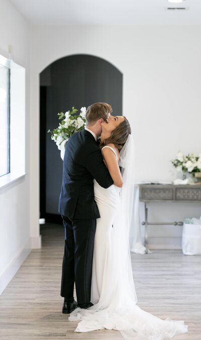 groom holds bride as she tips her head back and laughs