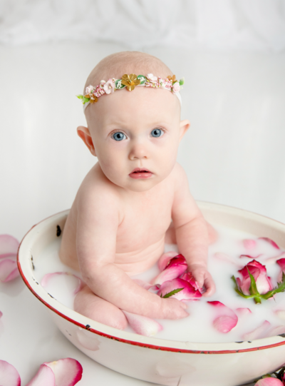 Baby girl looking at the camera while taking a milk bath for her photo session in St Louis MO