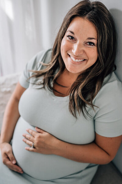 A pregnant mama smiles up at the camera during an in home lifestyle pregnancy photo shoot in Minneapolis.