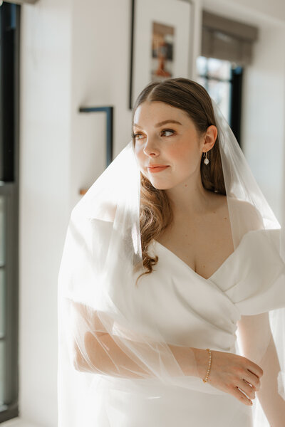 Bride looking away while holding veil