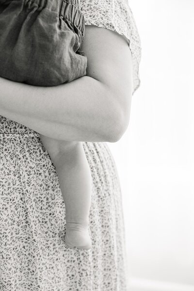 black and white close up on mother holding baby in her arm with his leg dangling down, Indianapolis Photographer