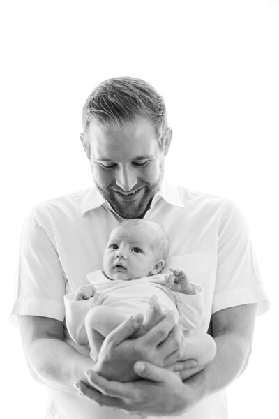 Dad holding happily his newborn baby. Photo in black and white. 
