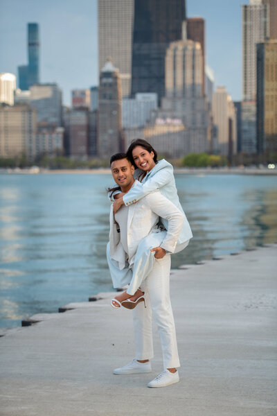 Indian couple in love having piggy  back ride by Lake Michigan surrounded by tall  skyscrapers