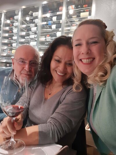 Maria Cristina Barrero and a male and female guest enjoying a gourmet wine tasting with a glass of red wine.