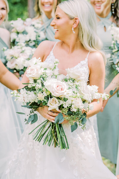 Bride in white dress holding bouquets of pink and white flowers