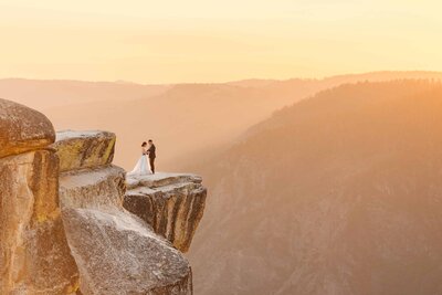 couple standing at taft point during a beautiful pink sunset in bridal attire