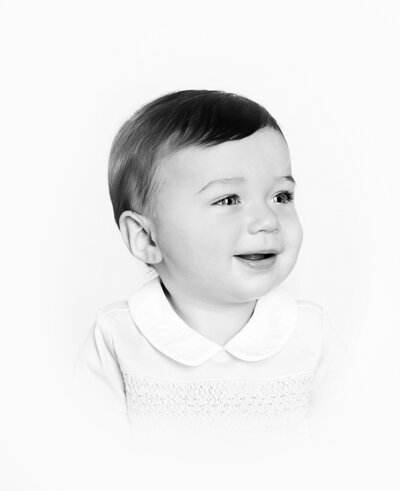 neutral tan and cream set up in studio of newborn baby girl smiling at the camera.