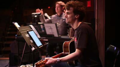 Guitar Player sitting on stage during a performance.