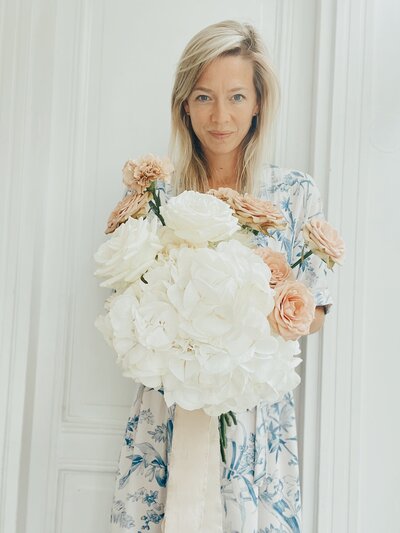 Flower Stylist Michèle heeft een boeket vast met witte hortensia's, roze rozen en roze anjers