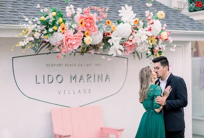 Engaged couple share a kiss during engagement session in the Lido Marina Village in Newport Beach