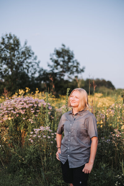 twin cities non-binary student in a field of flowers for their senior photos