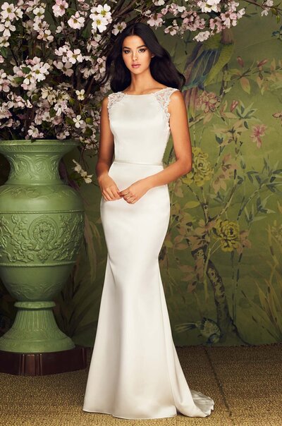 Paloma Satin and Guipure Lace Wedding Dress. Sleeveless Paloma Satin gown with bateau neckline. Guipure Lace at shoulders and armholes, continuing on to illusion lace back. Fabric belt along front of gown. Fit and flare satin skirt. Available Colours: Natural.