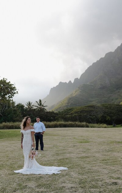 bride and groom standing in front of mountain in kauai
