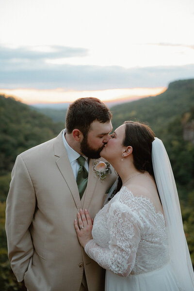 Arkansas elopement photo of bride and groom kissing on an overlook at sunset at Petit Jean Mountain State Park