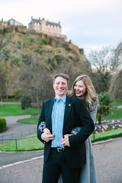 engaged couple smiles under castle