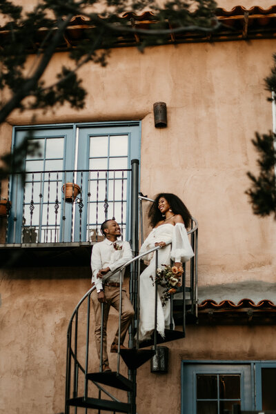 black couple standing on spiral stair case in wedding attire