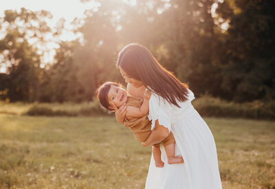 Family session photo of woman holding baby during golden hour