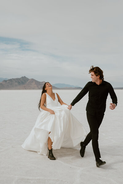An elopement couple runs through the Bonneville Salt Flats near Salt Lake City, Utah.