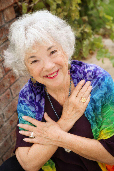 Close up image of Dr. Samarah in rainbow shaw smiling at camera with her arms crossed