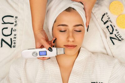 girl in white robe and hair in towel having  an aesthetics procedure on face