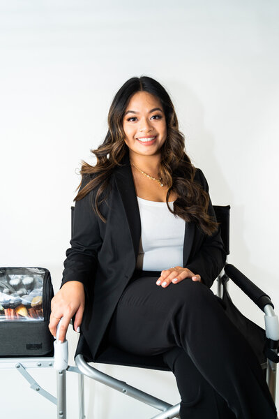 Sothana, licensed esthetician at Book Sothana in Jacksonville, FL, smiling while seated in a modern beauty studio.