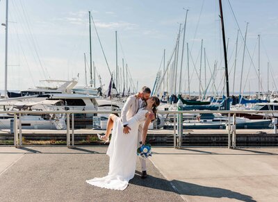 Groom, dipping bride down for a kiss with sunset railroad tracks in the background in South Seattle