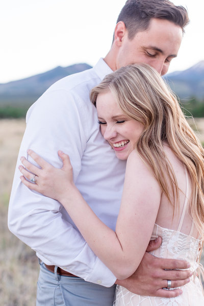 Girl hugging a man and laughing in front of mountains in Flagstaff