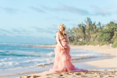 Mother to be in a gorgeous pink tulle gown on the beach at sunset.