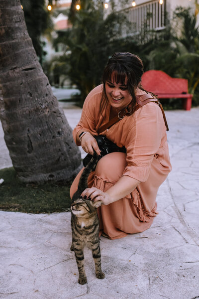 Kaitlin Powell Photography petting a cat at a wedding in Mexico.