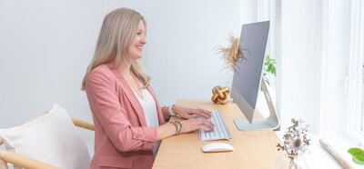 Maureen sitting at desk working on mac computer