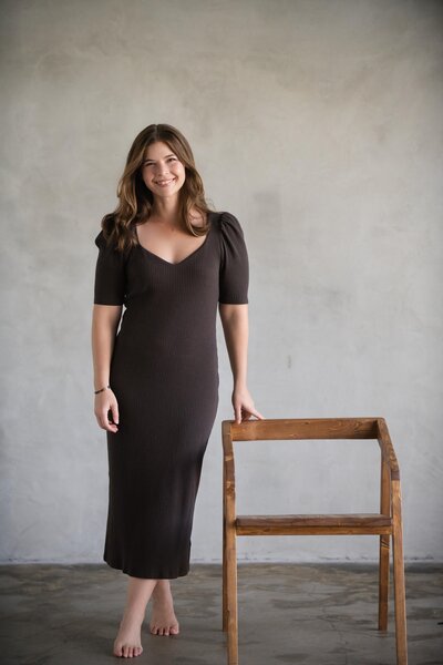 woman in blue skirt leaning against chair