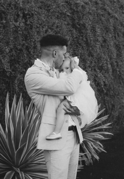 A tender black-and-white moment of a groom holding his daughter close, highlighting the emotional depth captured in Seattle wedding photography.