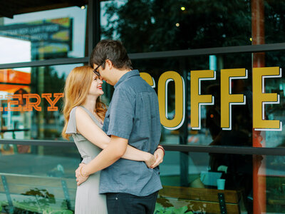 couple hugging forehead to forehead in front of a coffee shop