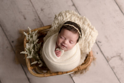 Swaddled Baby Girl Smiling In Basket Holding Heart
