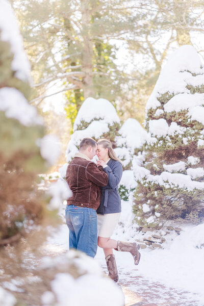 Newly engaged couple dance and snuggle in the snow at susnet