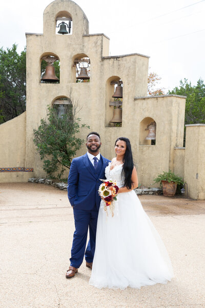 An Austin-based wedding photographer captures a bride and groom standing in front of an old church.