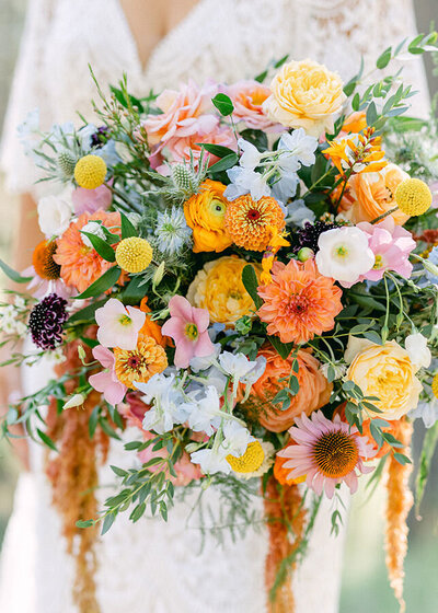 This image showcases a bride holding her wedding bouquet amidst the lush Mount Rundle Meadows in Banff National Park. The vibrant flora and scenic backdrop encapsulate the natural elegance and tranquility of her wedding day setting.