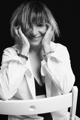 Portrait of a lady in a white shirt sitting on a white chair.