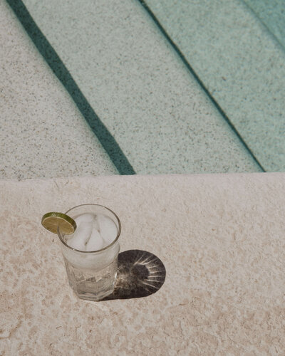 A cocktail with lime sitting beside a pool