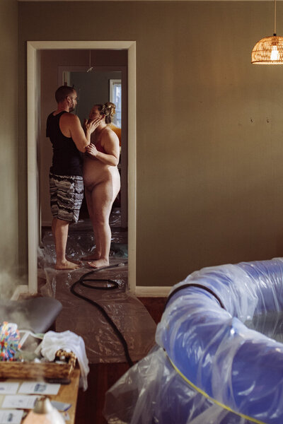 Tifton, GA birth photography: husband comforting wife as they stand in a doorway during labor