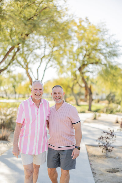 A joyful, sunlit moment between two men radiating love and happiness in Palm Springs. Their coordinated pink outfits perfectly complement the vibrant, warm desert landscape, capturing a celebration of love, connection, and timeless style.