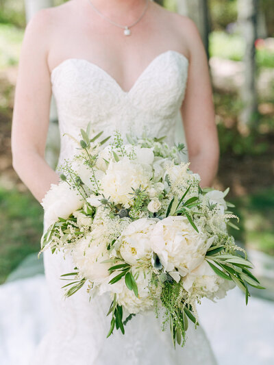 Close up of a bride holding a large white and green bouquet