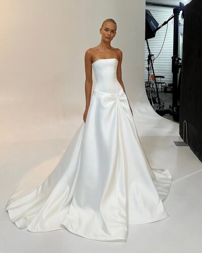 Meet Aspen, your sure-fire sartorial showstopper. Crafted from a luxe and luminous duchess satin, Aspen brings a Y2K refresh to a ballgown aesthetic. A straight neckline, dropped waist bodice sculpts the figure, whilst a soft A-line skirt sits effortlessly at the low waist. Finished with a drape detail at the asymmetric dipped waist, Aspen is available with or without a split.