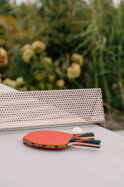 A ping pong table with two red paddles and a ball sitting near the center net