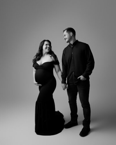 Couple’s maternity session with woman in sleek off-shoulder black gown